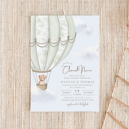 Baby shower invitation with hot air balloon and teddy bear design on a textured surface