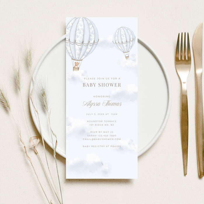 Baby shower invitation card on a glass plate with cutlery and dried flowers.