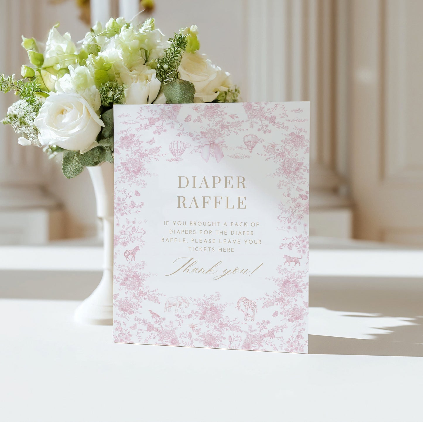 Table Sign with floral design next to a vase of flowers on a white surface.