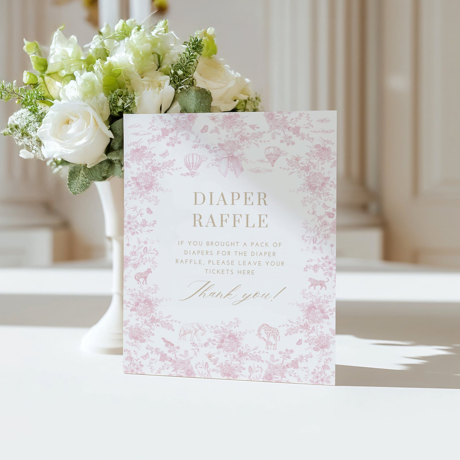 Table Sign with floral design next to a vase of flowers on a white surface.