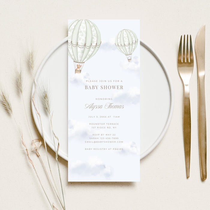 Baby shower invitation card on a glass plate with cutlery and decorative elements.