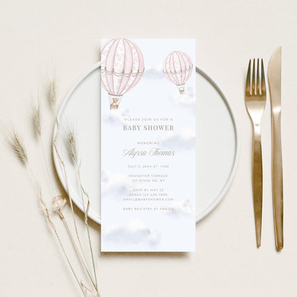 Baby shower menu card with hot air balloons on a white plate with cutlery