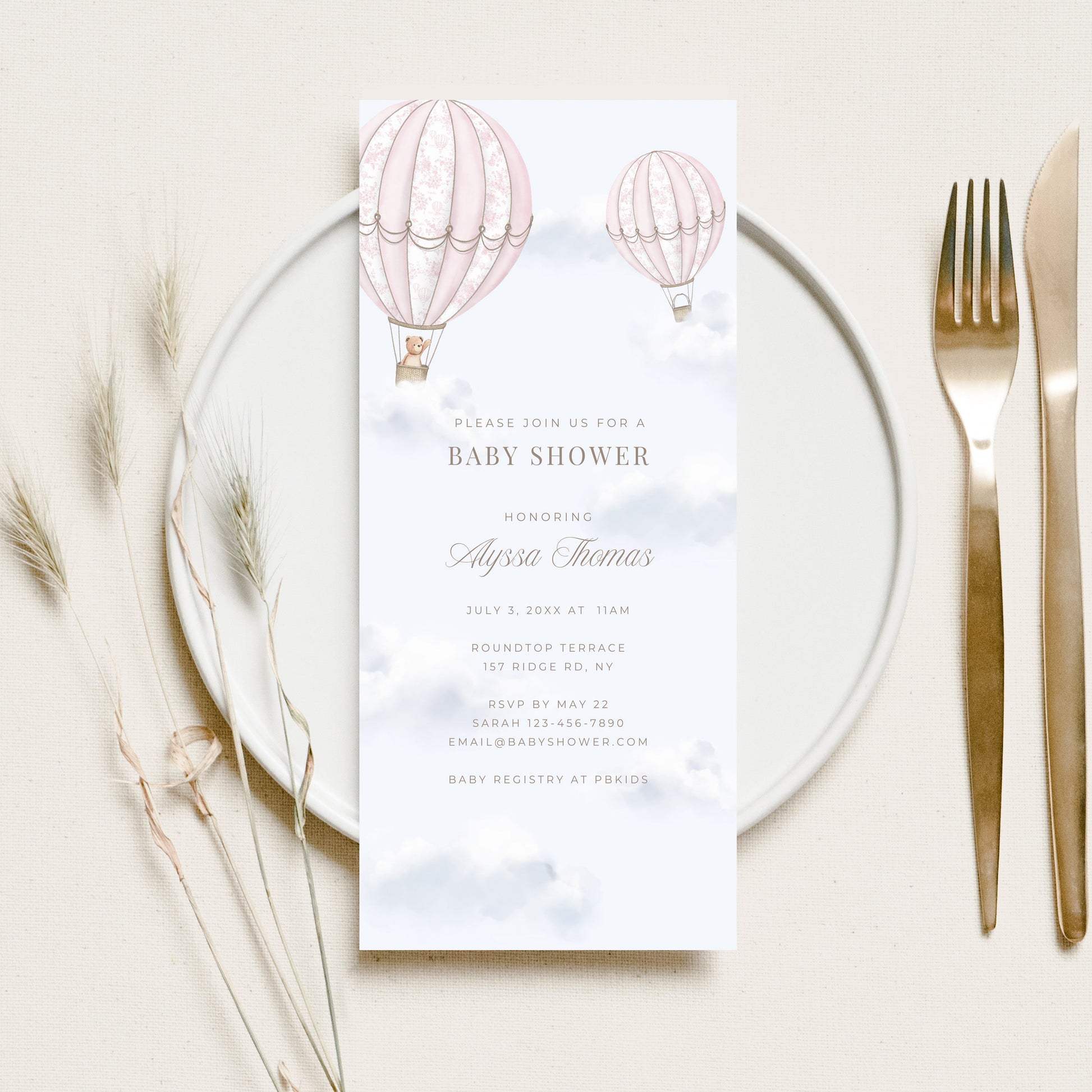 Baby shower invitation card with hot air balloons on a white plate with cutlery