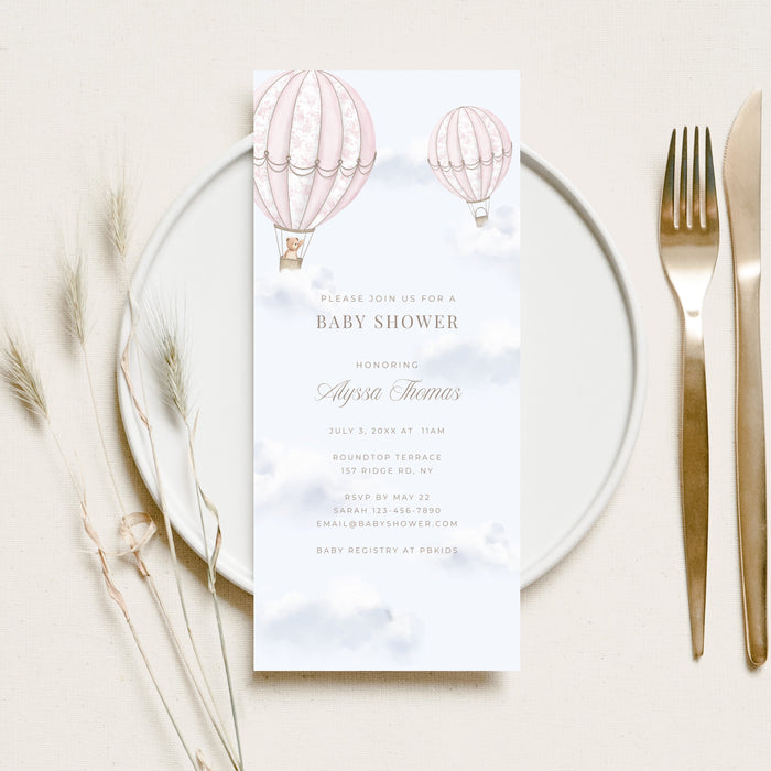 Baby shower invitation card with hot air balloons on a white plate with cutlery