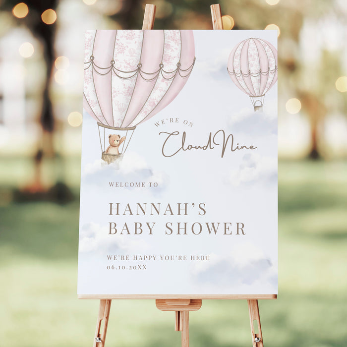 Baby shower welcome sign on an easel with hot air balloon design outdoors.