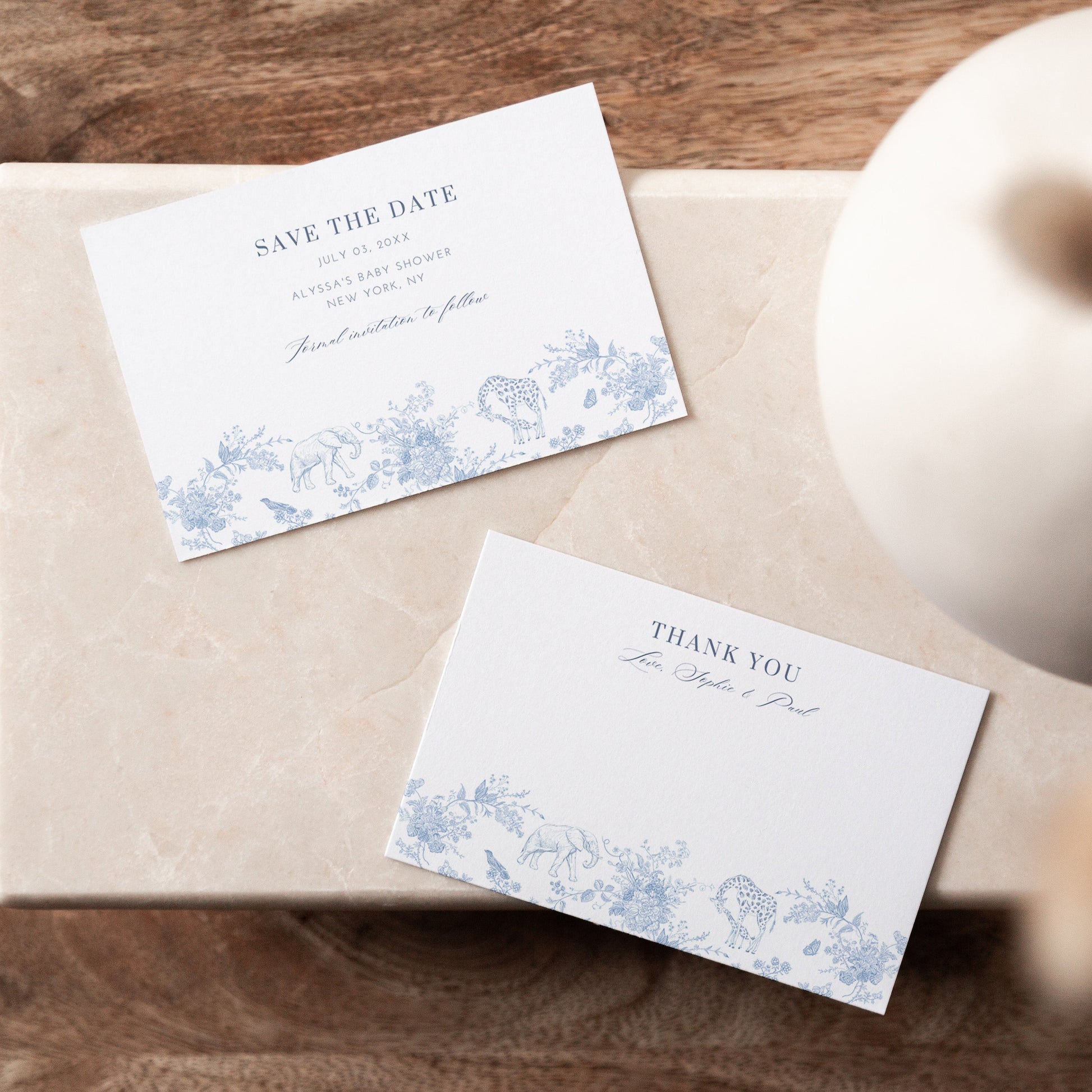 Two cards on a wooden surface with a vase in the background
