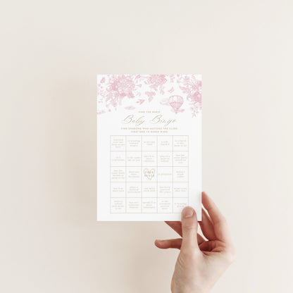 Hand holding a Baby Bingo Game Card with floral design on a light background