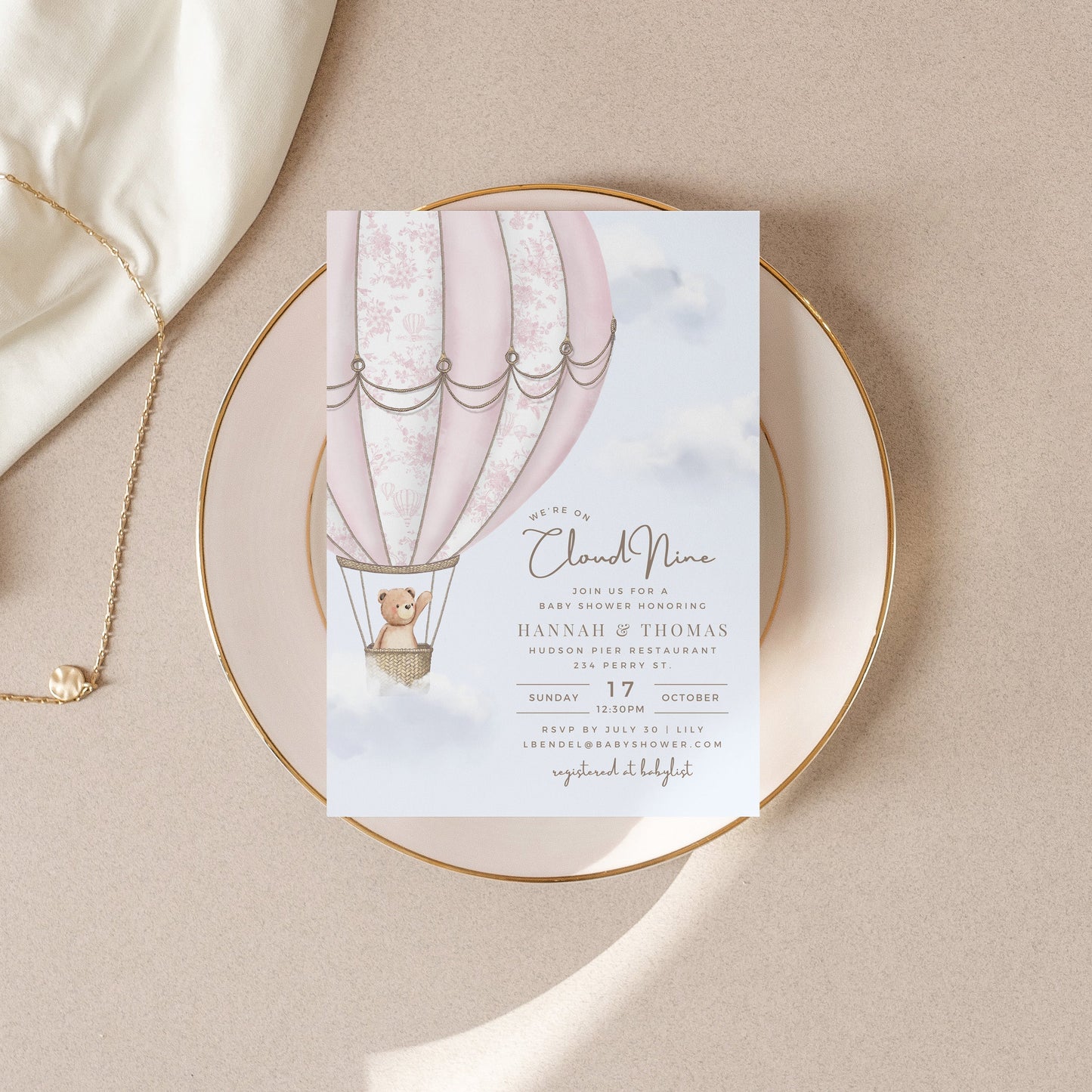 Baby Shower invitation card with hot air balloon design on a beige surface