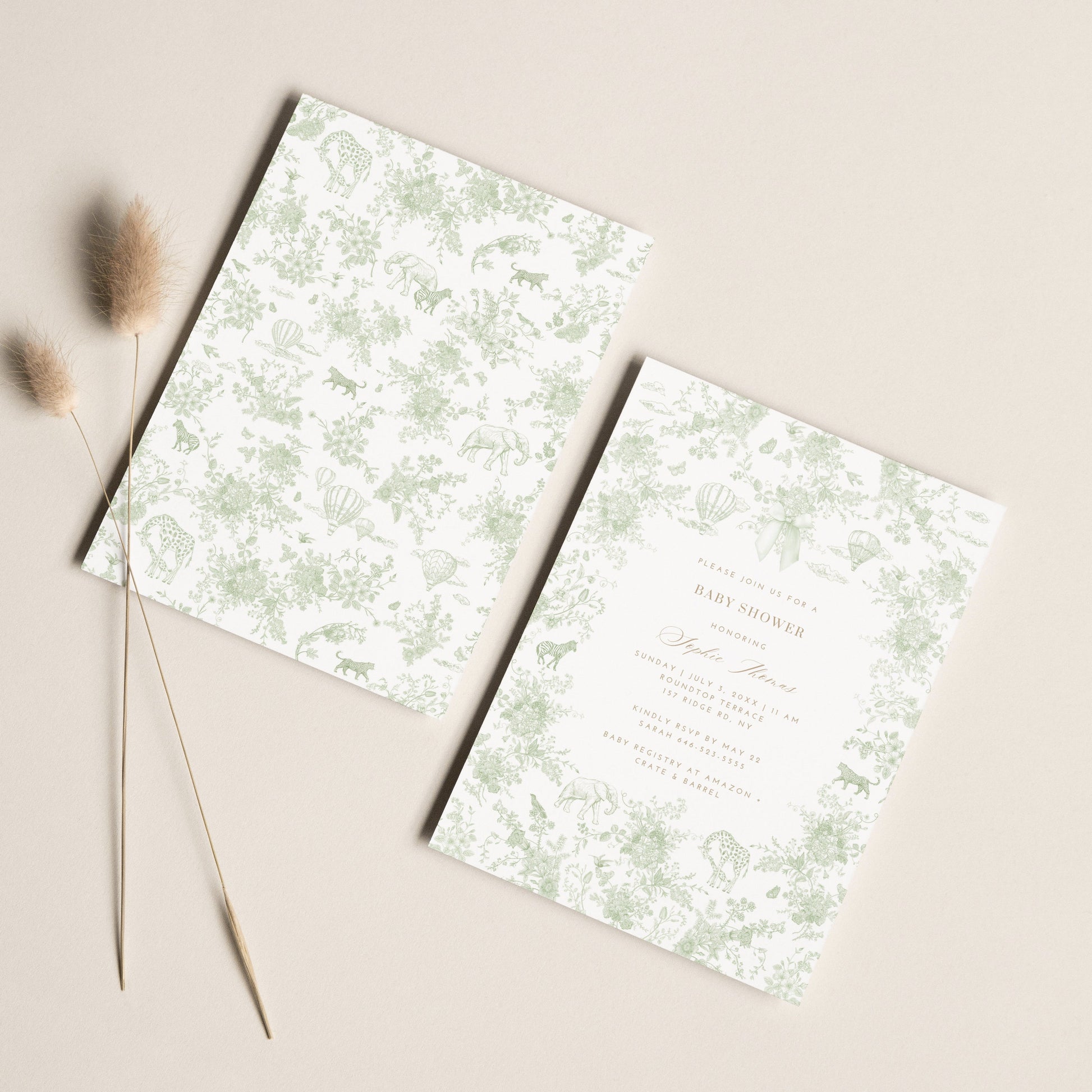 Two floral patterned baby shower invitation cards on a beige surface with dried grasses.