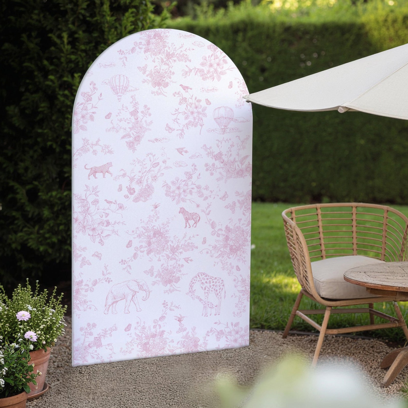 Decorative pink floral backdrop in a garden setting with a wicker chair and table.