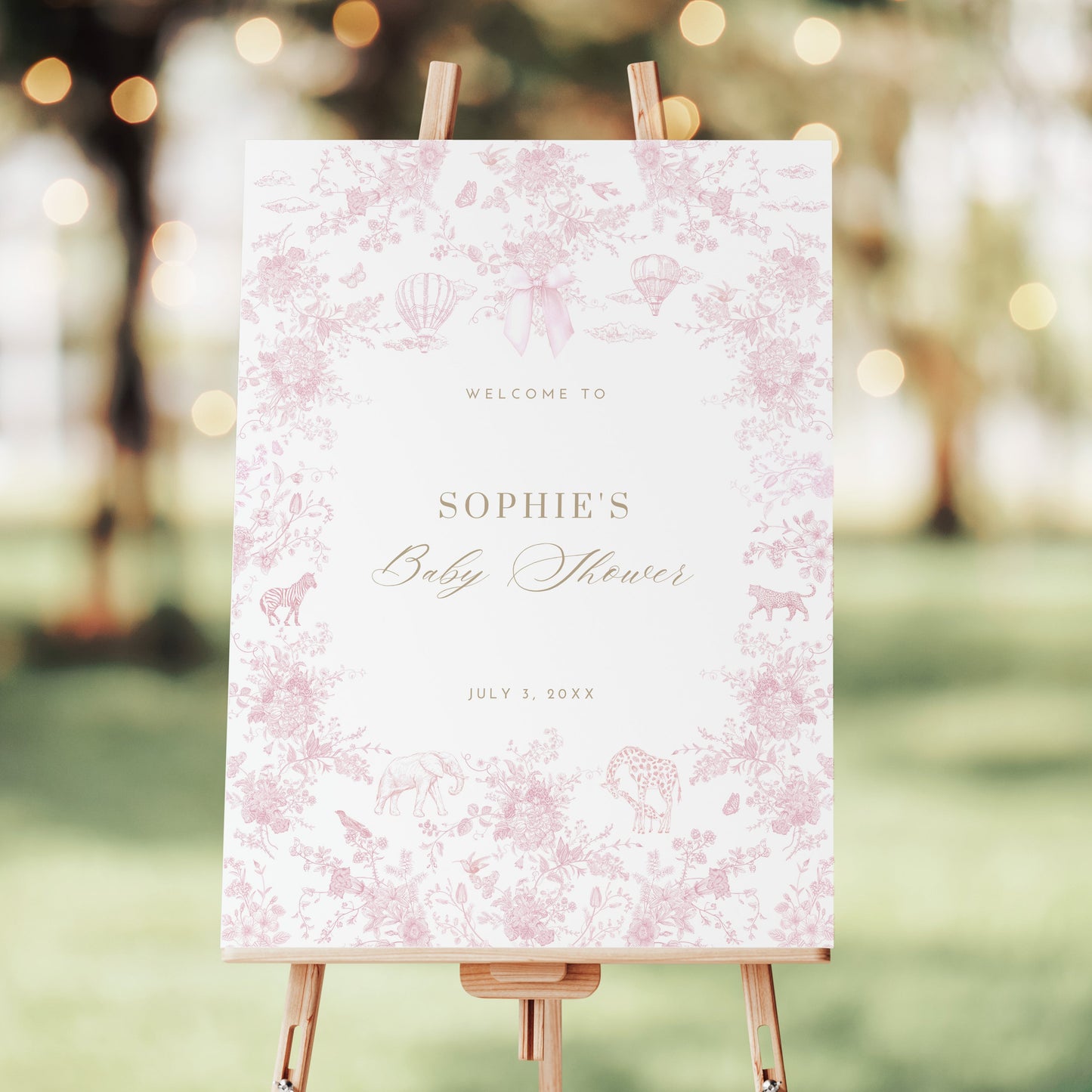 Baby shower welcome sign on an easel with a pink floral pattern in an outdoor setting