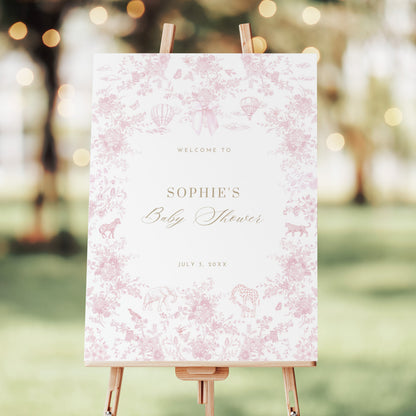 Baby shower welcome sign on an easel with a pink floral pattern in an outdoor setting