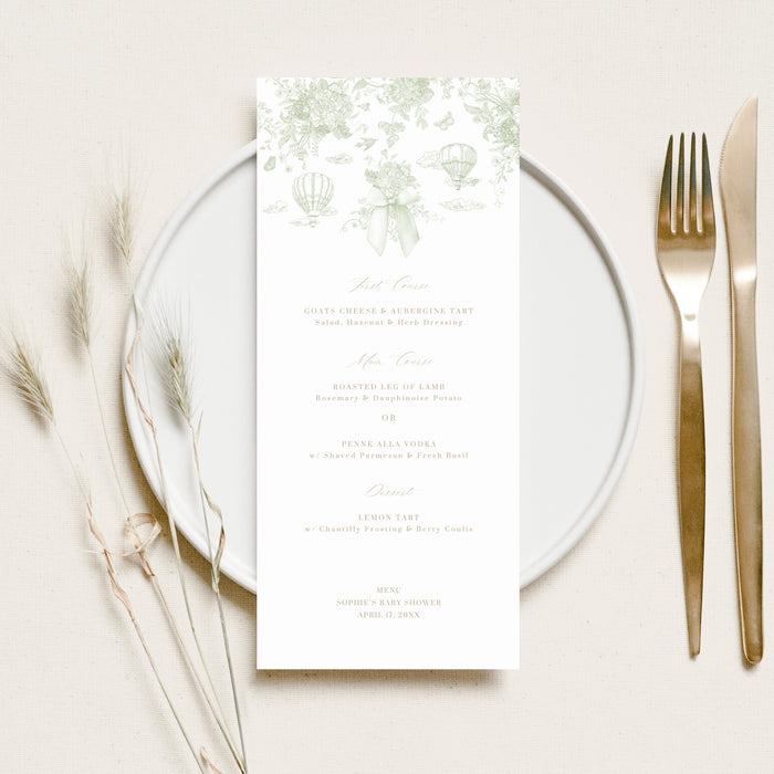 Place setting with a menu card on a white plate, fork, and knife on a light background