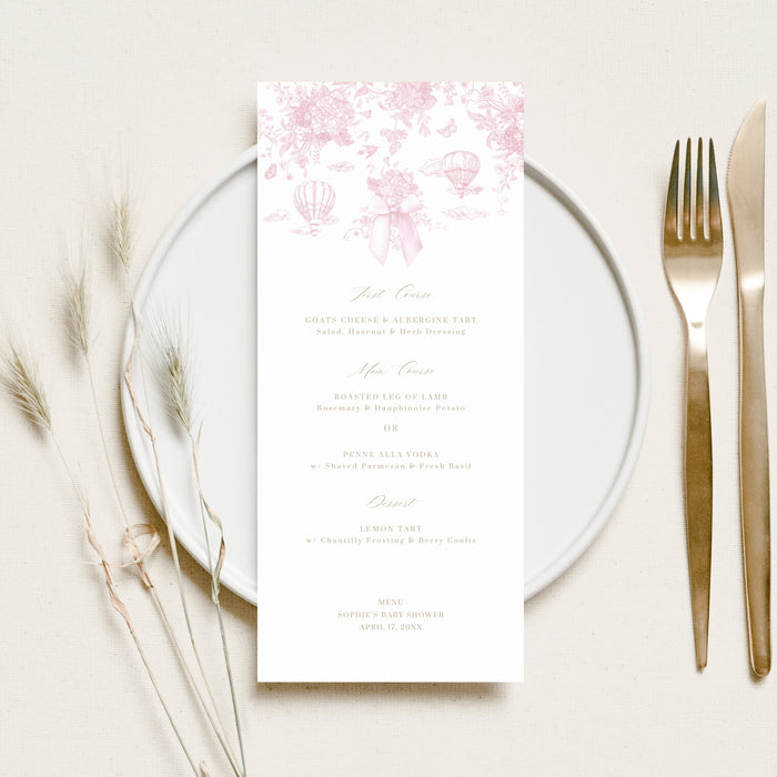 Place setting with a floral menu card on a white plate, accompanied by a fork and knife.