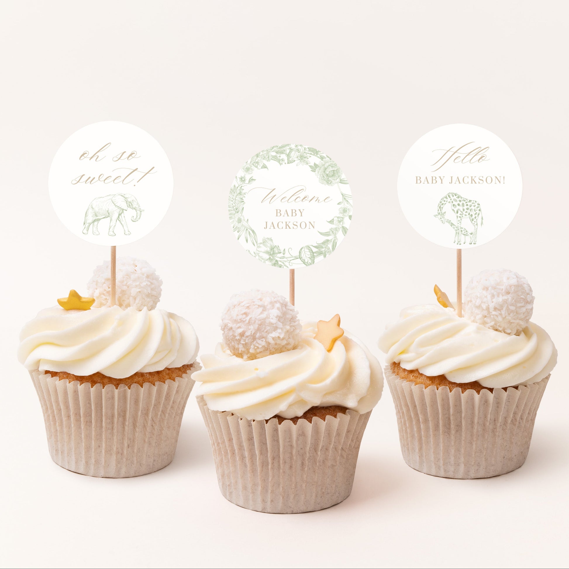 Three cupcakes with white frosting and decorative toppers on a light background
