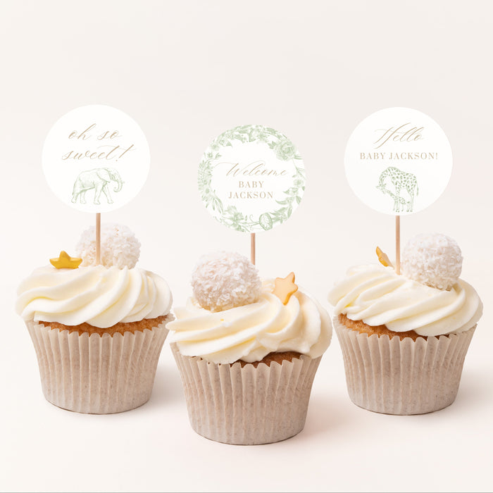 Three cupcakes with white frosting and decorative toppers on a light background