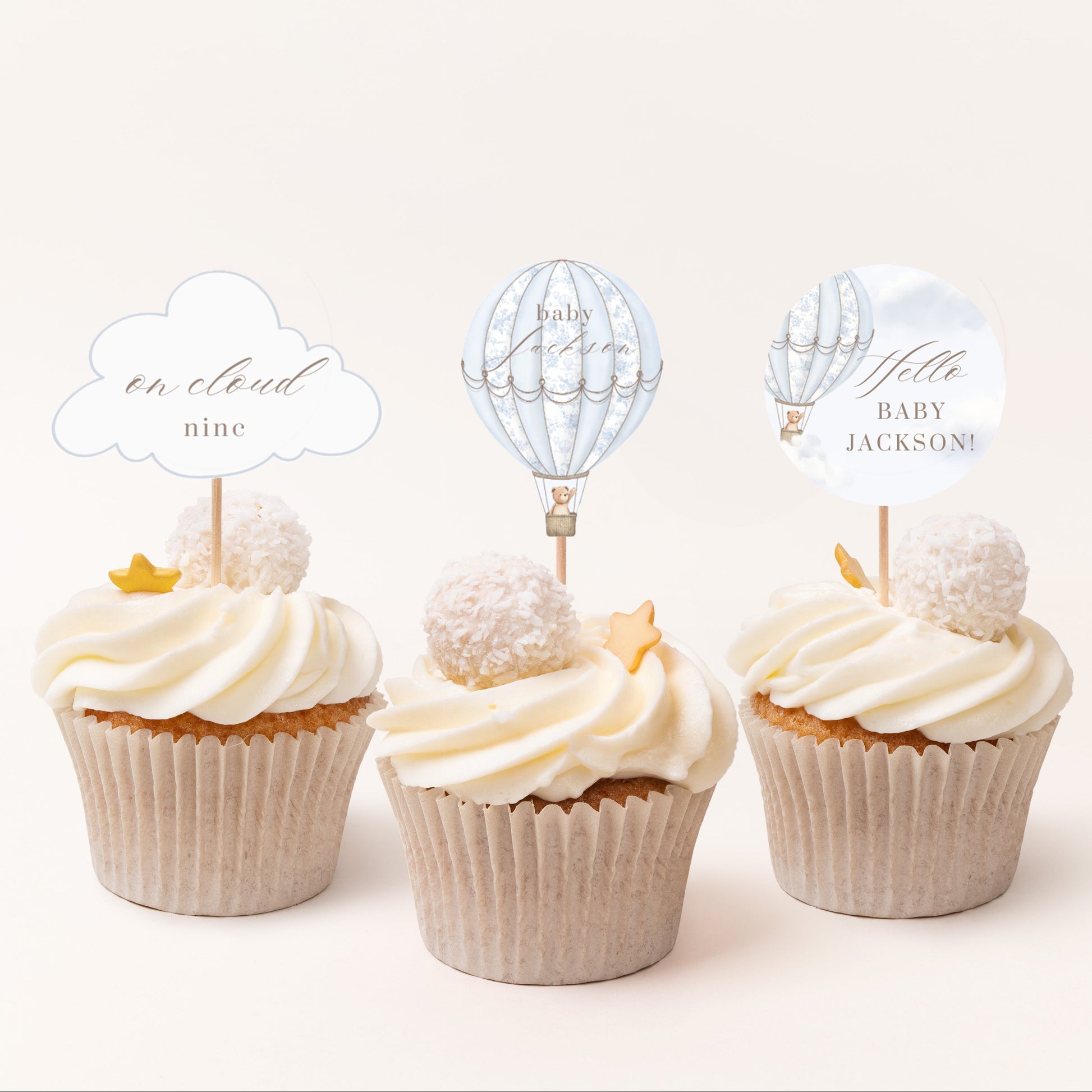 Three cupcakes with decorative toppers on a white background