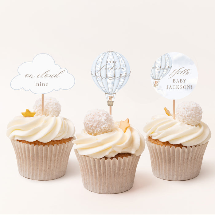 Three cupcakes with decorative toppers on a white background