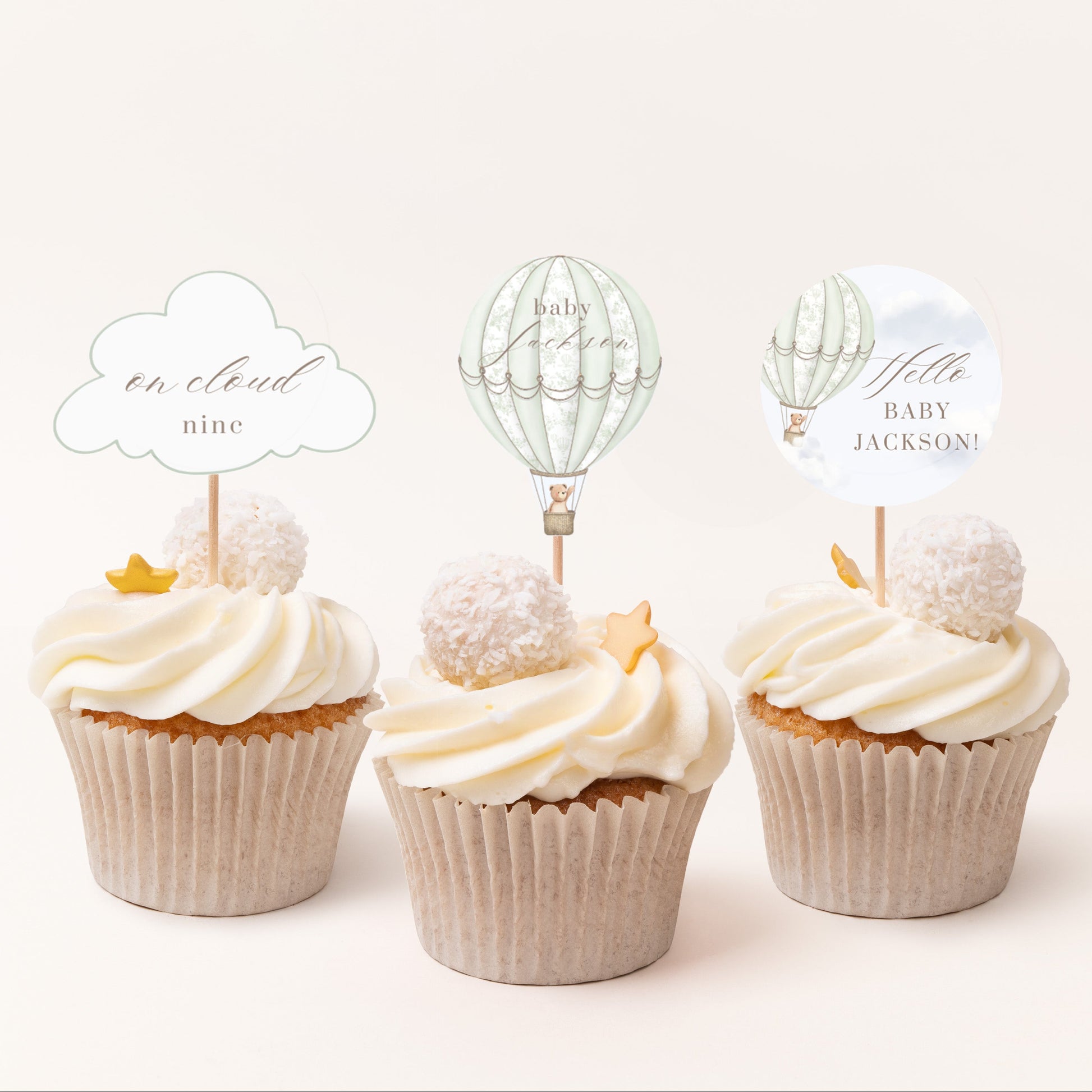 Three cupcakes with decorative toppers on a white background