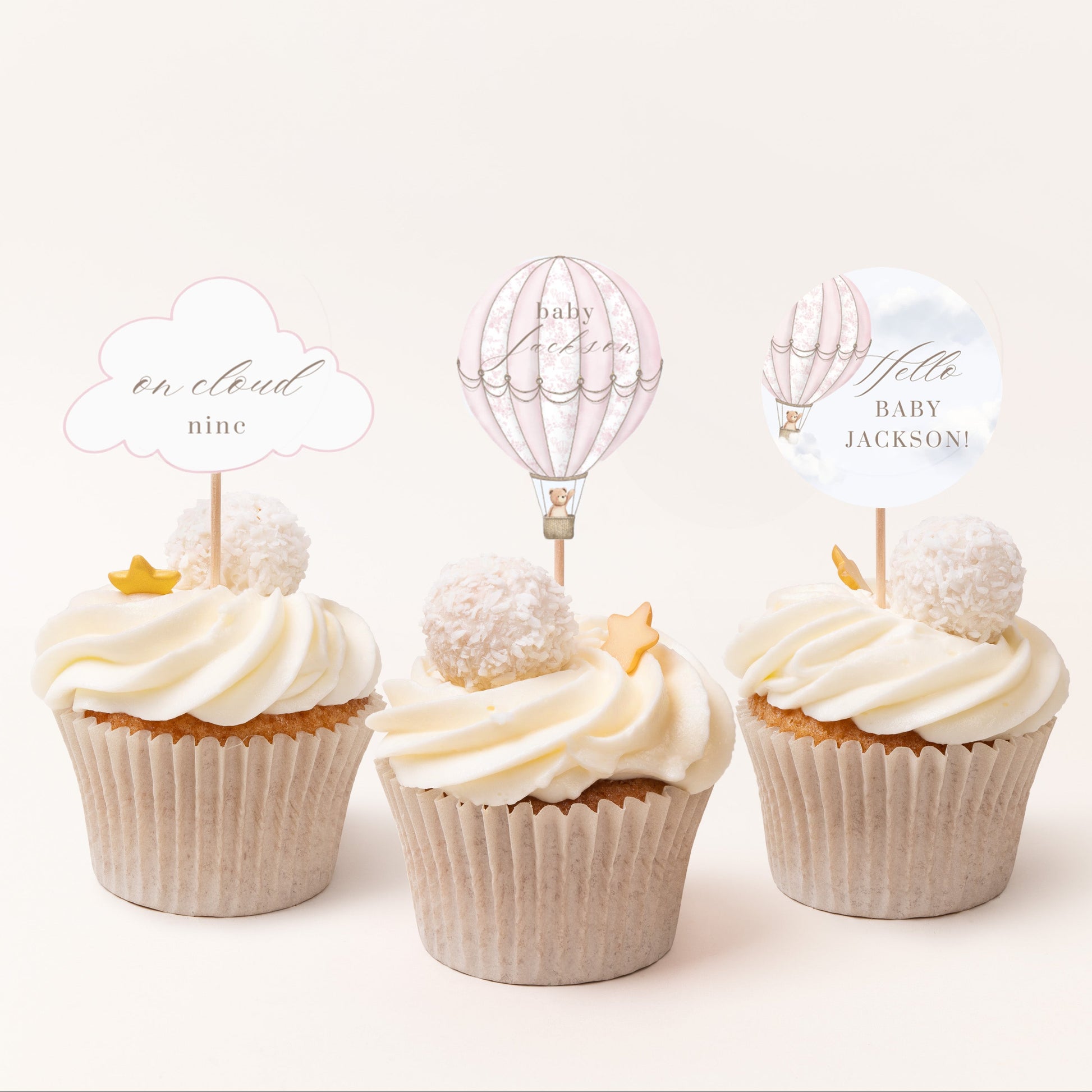 Three cupcakes with decorative toppers on a white background