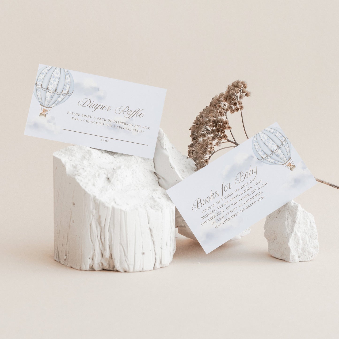 White stone holder with baby shower Diaper Raffle and Books for Baby cards on a beige background