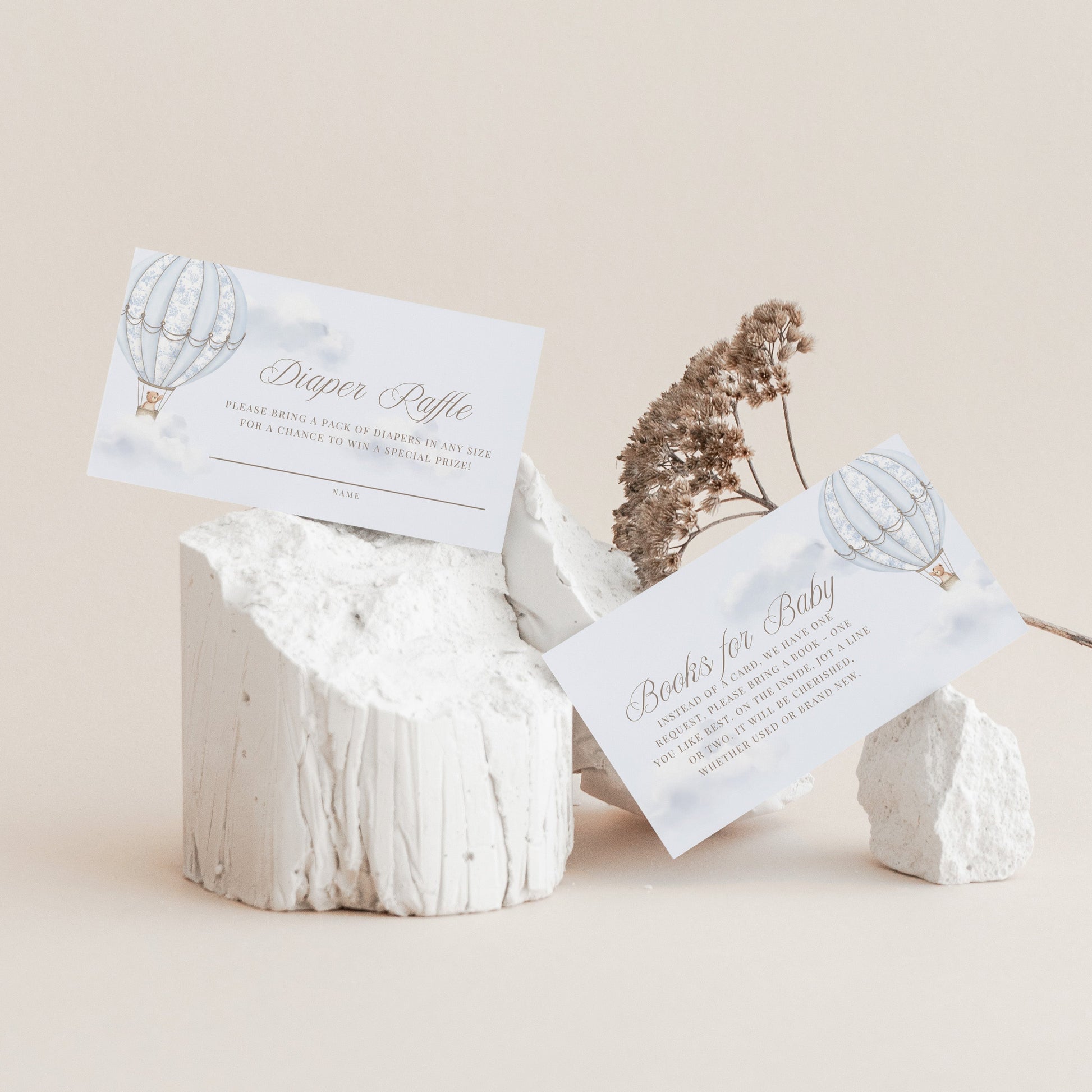 White stone holder with books for baby and diaper raffle card on a beige background